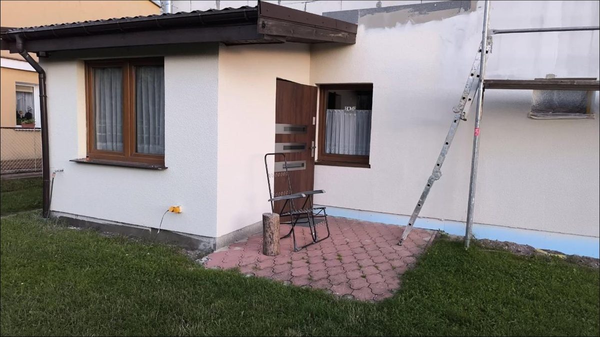 Dom z wykończoną elewacją, obok rusztowanie przy drugiej ścianie