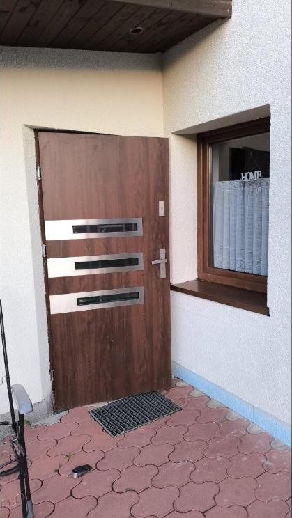 Wejście do domu z nowymi drzwiami i wykończoną ścianą